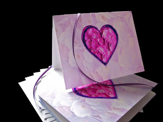 A Valentine card with a heart full of pink flower petals on a pale lavender background of petals.