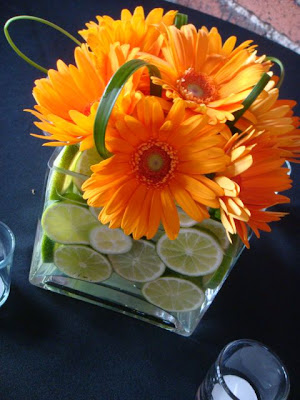 Third cube vases filled with sliced limes bright orange gerber daisies