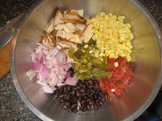 large silver bowl with chicken, diced red onions, black beans, pickled jalapeno, tomatoes, and corn