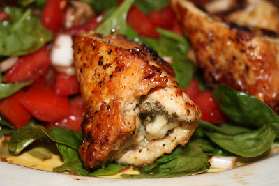 close up of one pesto chicken roll laying on spinach salad