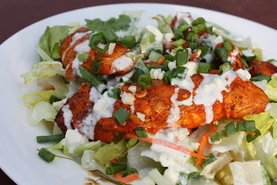 plate of lettuce and shredded carrots with buffalo chicken and blue cheese dressing