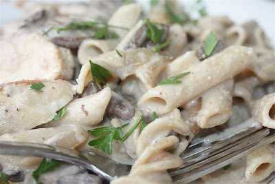 fork holding pasta covered in creamy sauce with mushrooms