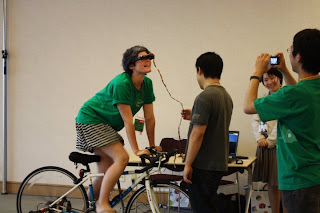 自転車で Gogole Earth 内を飛び回る展示作品を示す画像。