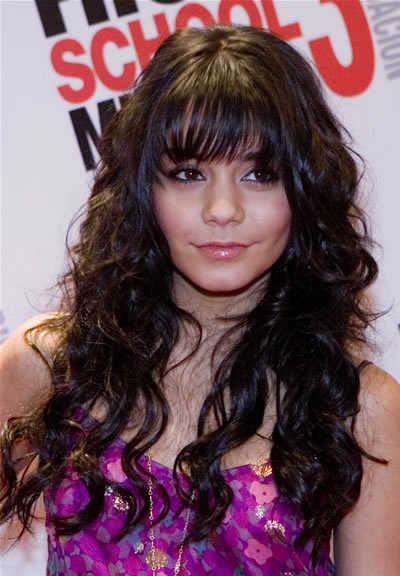 In this photo, this actress has curly hair plus a straight-across bang,