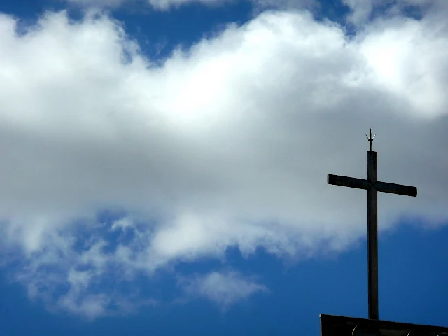 Una cruz y nubes adorándola.