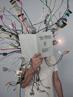 child holding up book entitled the power of books, with wires coming out of it.
