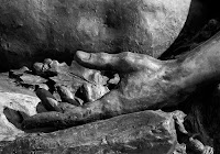 statue detail of a hand and some leaves resting on a rock