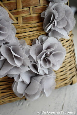 Collier de fleurs grises en tissu sur un buste en osier