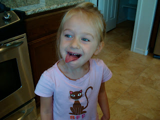 Young girl standing in kitchen licking her lips