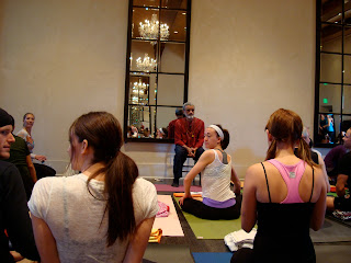 Dharma Mittra talking to room full of people on yoga mats
