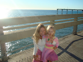 Woman and child on pier crouching showing ocean in background