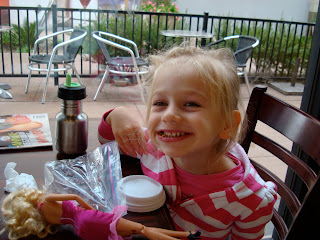 Young girl sitting at table smiling with toys and snacks