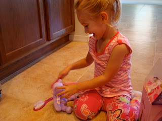 Young girl playing with purple small teddy bear