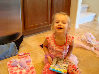 Young girl wearing beads holding book on floor