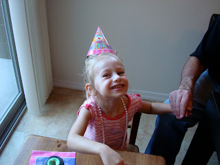 Young girl holding her dads hand smiling with birthday hat and necklace