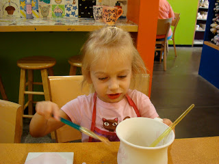 Young girl in pink painting a coffee mug