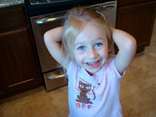 Young girl standing in kitchen with arms behind head