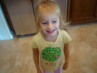 Young girl in yellow t-shirt standing in kitchen