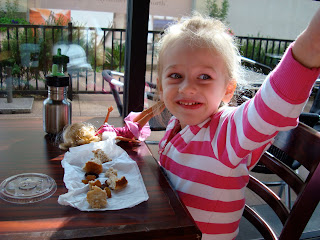Young girl at coffee shop at table pointing with snacks in front of her