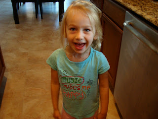 Young girl in blue shirt in kitchen smiling