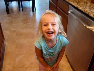 Young girl leaning forward smiling in kitchen