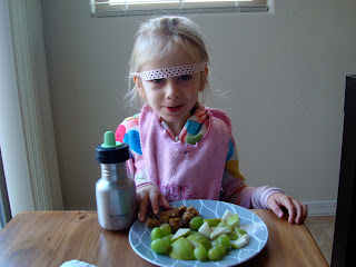 Young child at table with low riding headband eating snacks