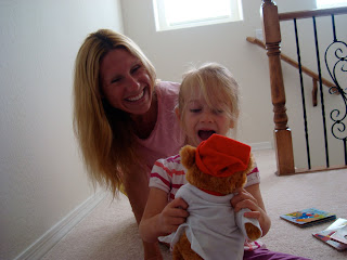 Woman and child smiling as she looks at stuffed animal
