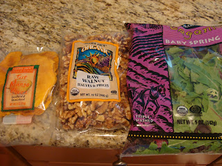 Packages of mango slices, raw walnuts and spring greens on countertop