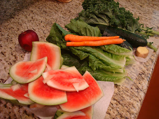 Rind of cut up watermelon on outer with carrots and greens