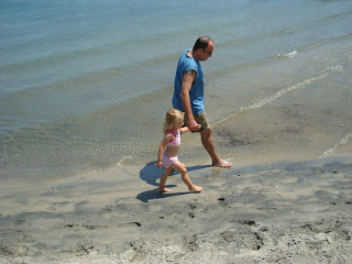Man and child walking along beach wading in water