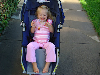 Young girl smiling in blue stroller on sidewalk