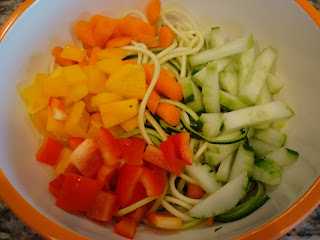 Carrots, peppers and cucumbers on top of zucchini in bowl