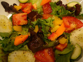 Mixed green salad topped with diced vegetables in dressing