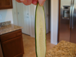 Hand holding on thinly sliced cucumber