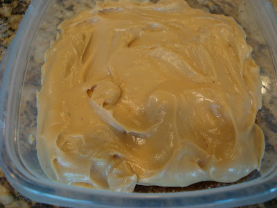 Cheesecake batter spread over crust in clear container