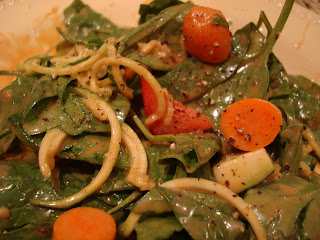 Spinach, zucchini noodles, mixed vegetables toped with peanut sauce in bowl