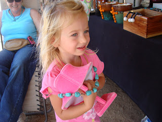 Young girl wearing pink holding a turquoise necklace 