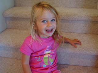 Smiling young girl sitting on steps in pink shirt