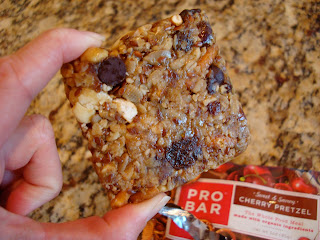 Hand holding portion of Pro Bar in Cherry Pretzel Flavor