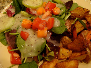 Mixed salad with dressing served with roasted potatoes and carrots on plate