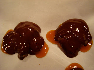 Two turtles with chocolate spooned over caramel on parchment paper