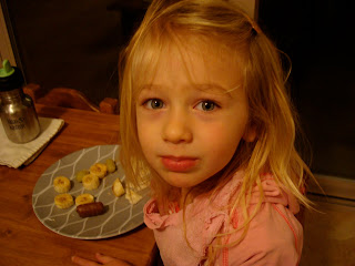 Young girl sitting at table sick eating snacks off of plate