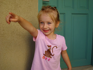 Little girl standing in front of blue door pointing - 7