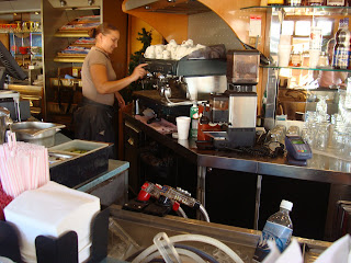 Cafe worker brewing coffee behind counter
