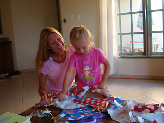 Woman and young girl sitting together unwrapping presents
