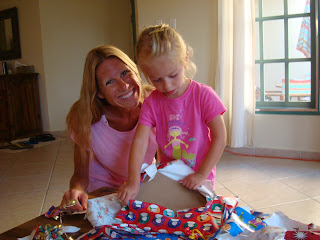 Woman smiling watching young girl unwrapping presents