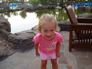 Young girl bending over smiling by water feature