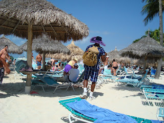 Man walking under palm tree huts on beach