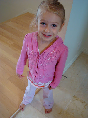 Young girl standing in pink zip up smiling