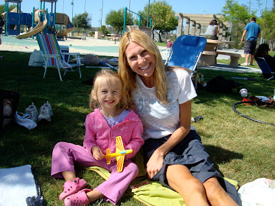 Woman and child sitting on grass outside of pool area